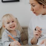 A joyful child and an adult engaged in learning at home, fostering creativity and connection.