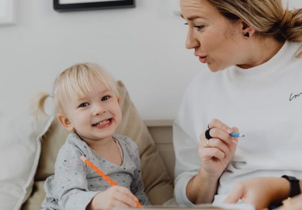 A joyful child and an adult engaged in learning at home, fostering creativity and connection.